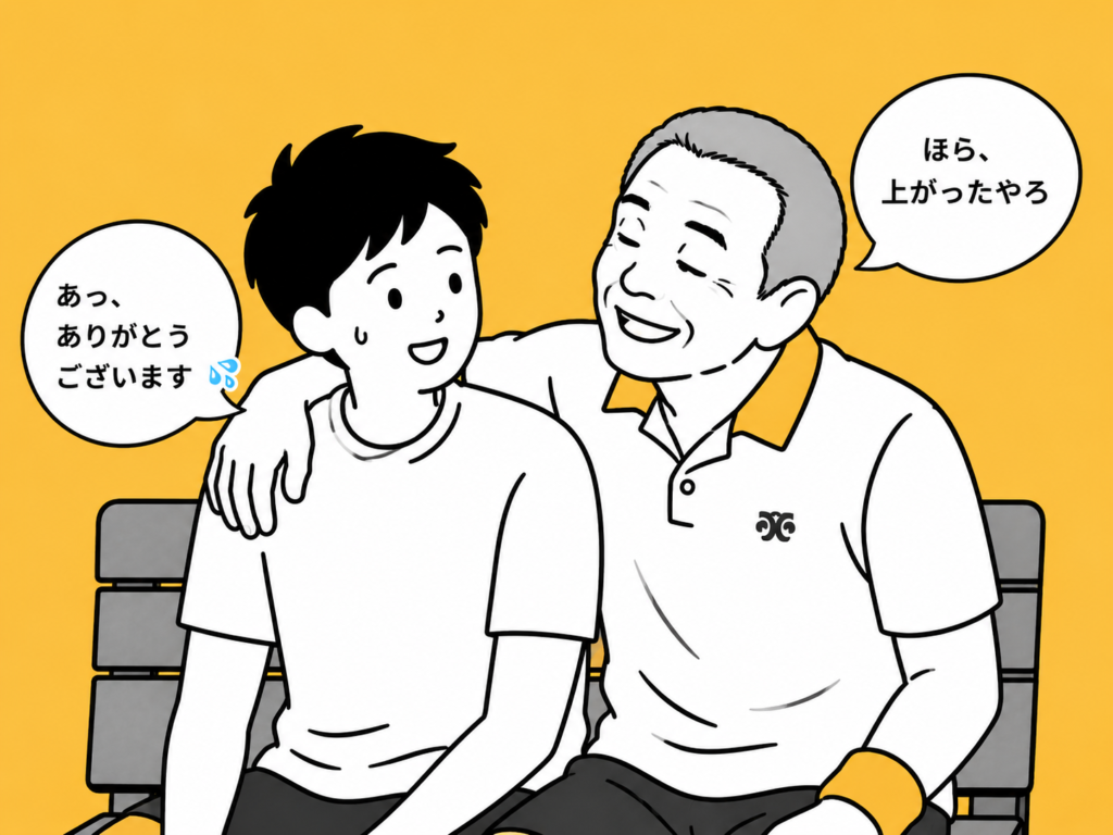 テニスコートのベンチで肩を組む年配男性と若い男性。年配男性が「ほら、上がったやろ」と笑顔で話しかけ、若い男性が苦笑いしながらお礼を言っている様子。